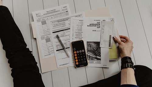 cell phone person holding paper near pen and calculator phone